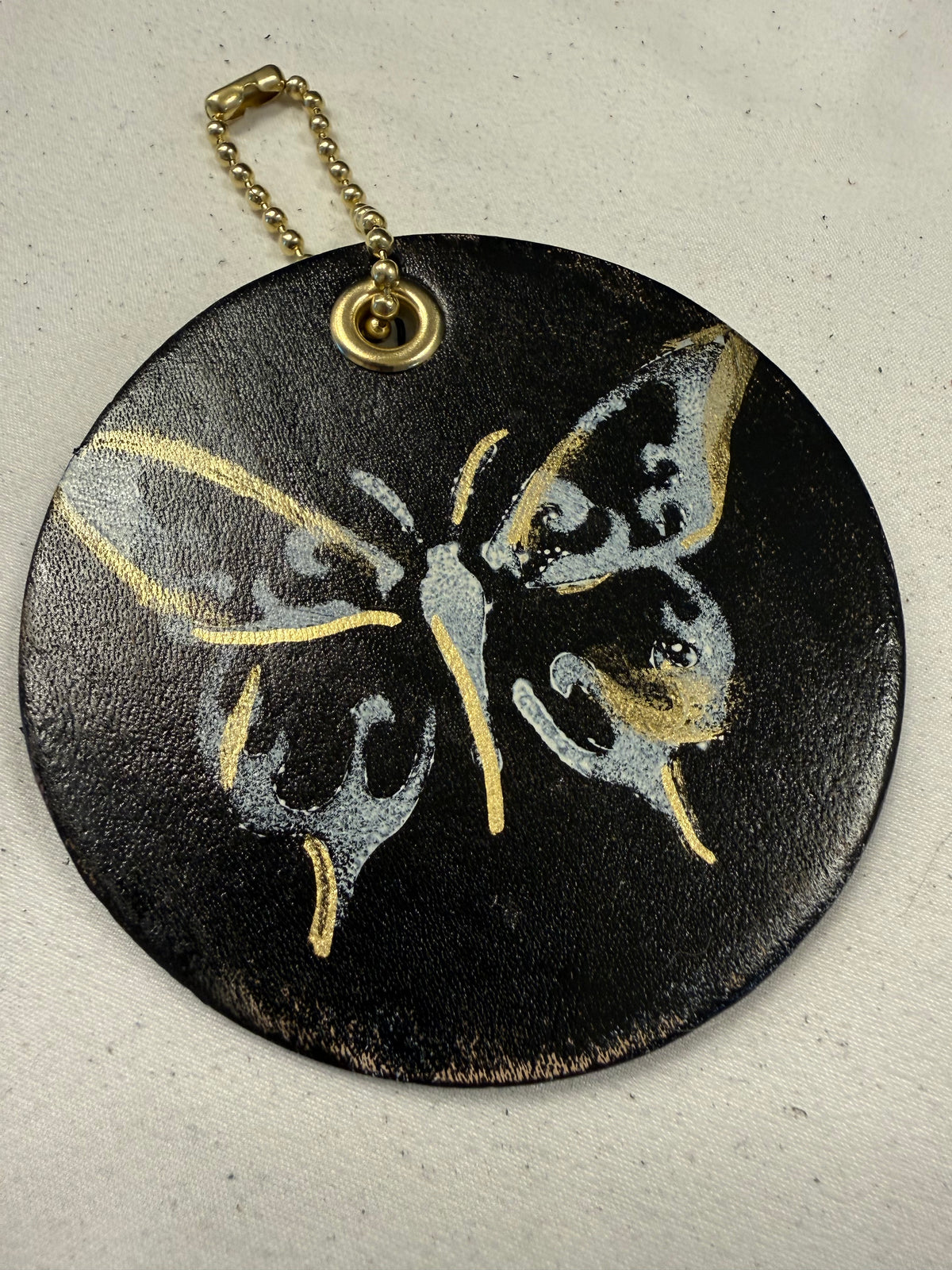 Stenciled and Painted Leather Disc with Butterfly and Skull Moth Charm