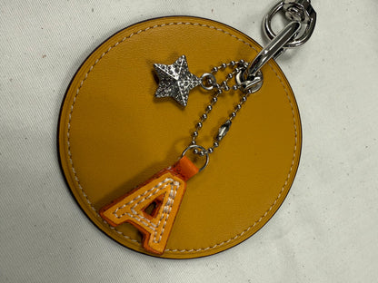 Repurposed Retro Coach Coaster with an A initial and a Coach Rhinestone Star Charm Bag Charm
